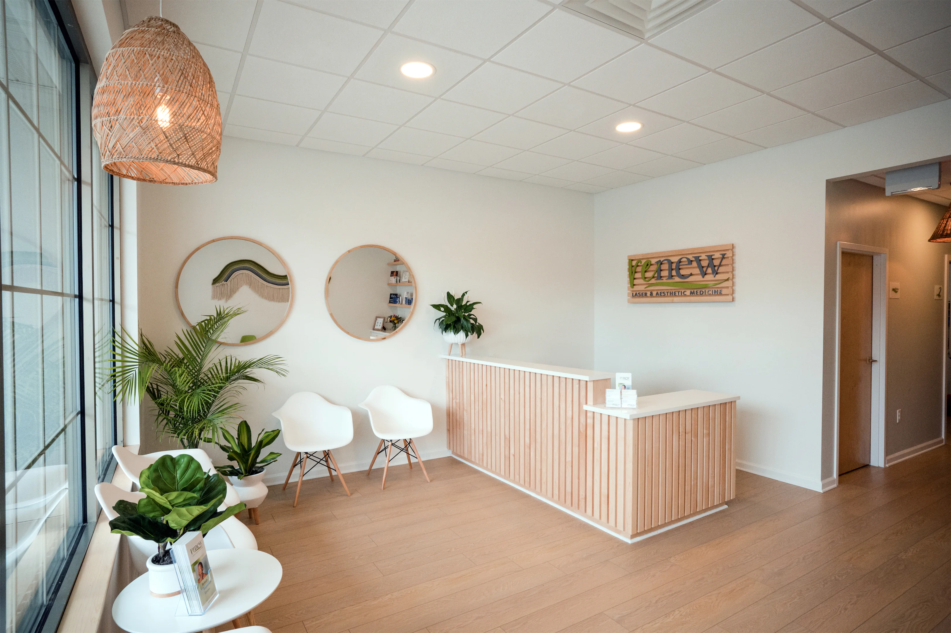 Modern luxury med spa lobby at Renew Laser & Aesthetic Medicine in West Chester, featuring a bright, natural wood reception desk, indoor plants, and soothing minimalist decor.